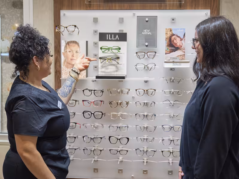 Ophthalmology Associates optical staff assisting patient during designer eyewear consultation at optical trunk show event